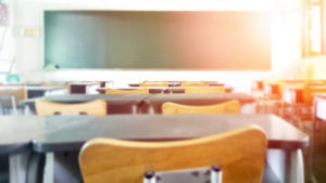 blurred empty elementary school classroom with sunlight shining in