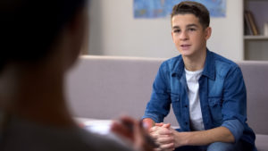 A young teen boy listens to a counselor in his office