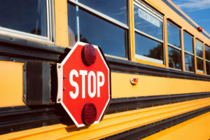 Stop sign with red lights on the side of the school bus