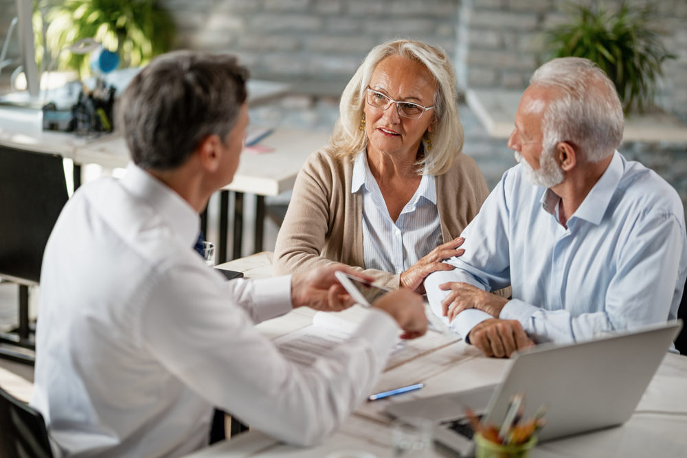 Senior couple communicating with insurance agent while having consultations with him in the office.