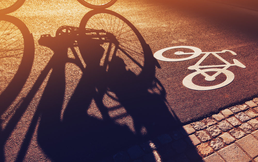 Shadow of unrecognizable cyclist riding a bike on bicycle lane 