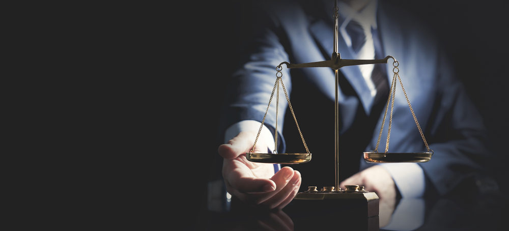 scale on a desk with lawyer in shadow