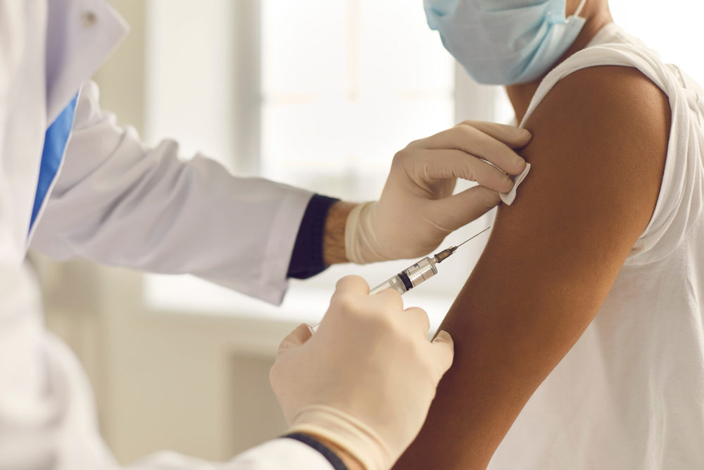 Doctor in medical gloves giving Covid-19, AIDS or flu antivirus vaccine shot to African-American patient