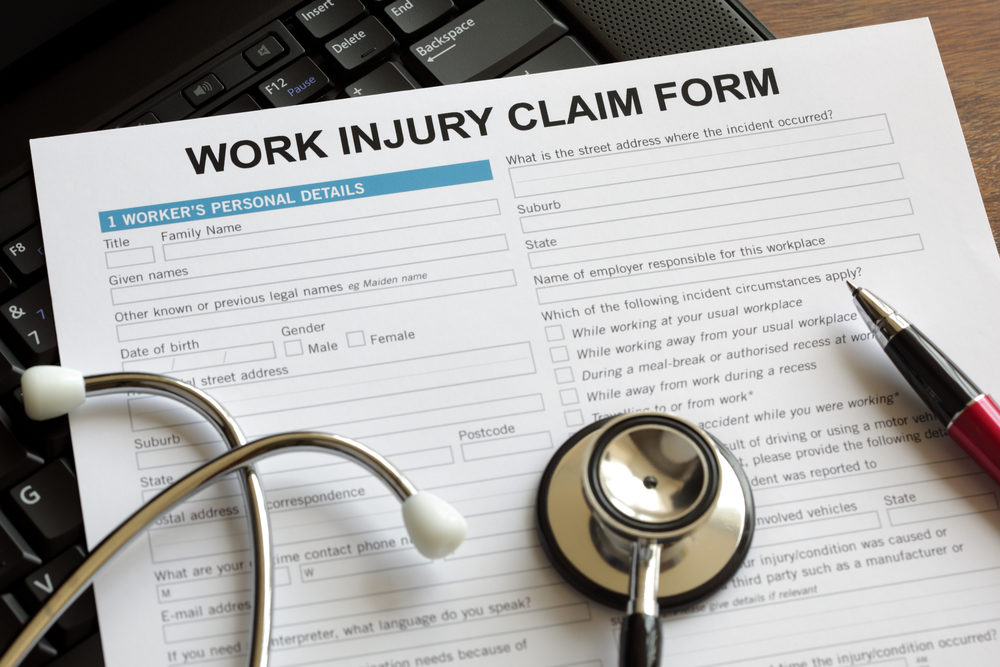 Food Production Workers in Ohio and Illinois Suffering Higher Rates of Injuries—OSHA Responds A stethoscope and pen rest atop a Work Injury Claim Form document