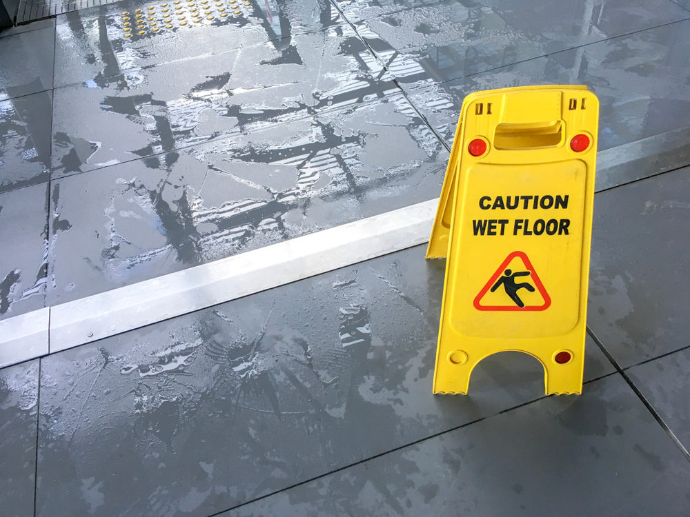 A yellow sign reading CAUTION WET FLOOR on a slippery looking wet floor