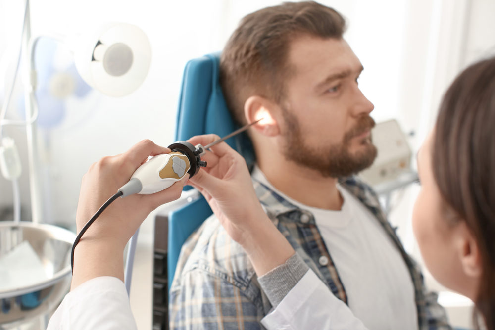 A doctor examine's a patient's ear with an ENT telescope