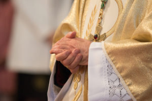 Catholic priest with his hands clasped together
