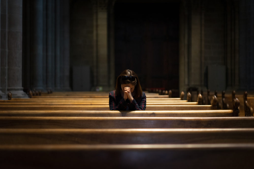 A girl alone in church pew, alone