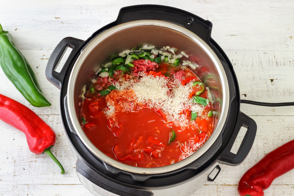 An Instant Pot filled with a mix of tomato, rice, and hot peppers