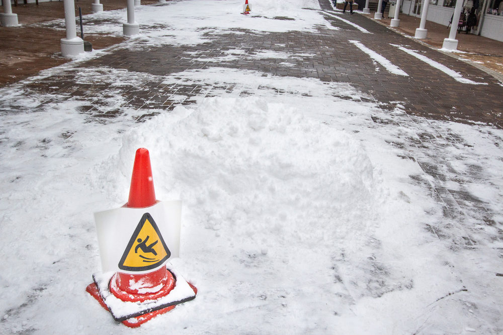 Can You Sue A Business for a Snow and Ice-Related Slip and Fall Injury? An orange cone warns of slippery conditions on a snow covered walkway