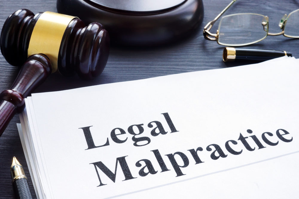 "Legal Malpractice" document on a desk with a gavel