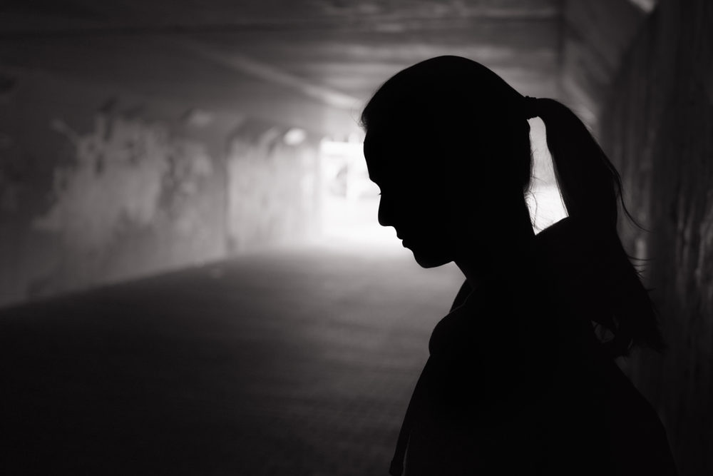 Silhouette of a young female standing in a dark tunnel