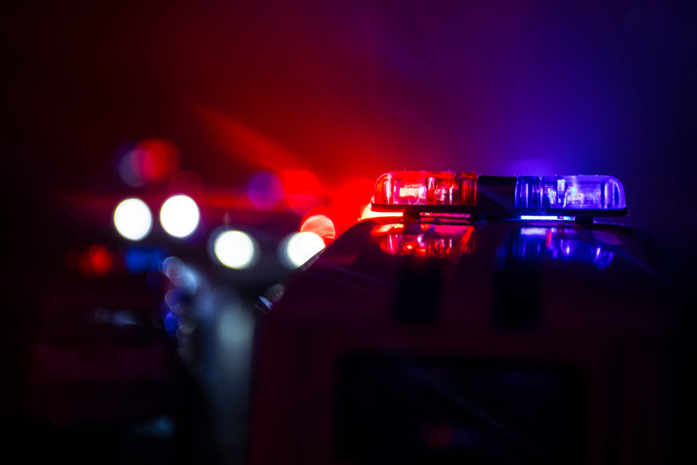 Red and blue lights on top of a police car illuminate the night