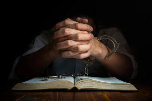 A mans hands are partially cuffed as he reads the Bible