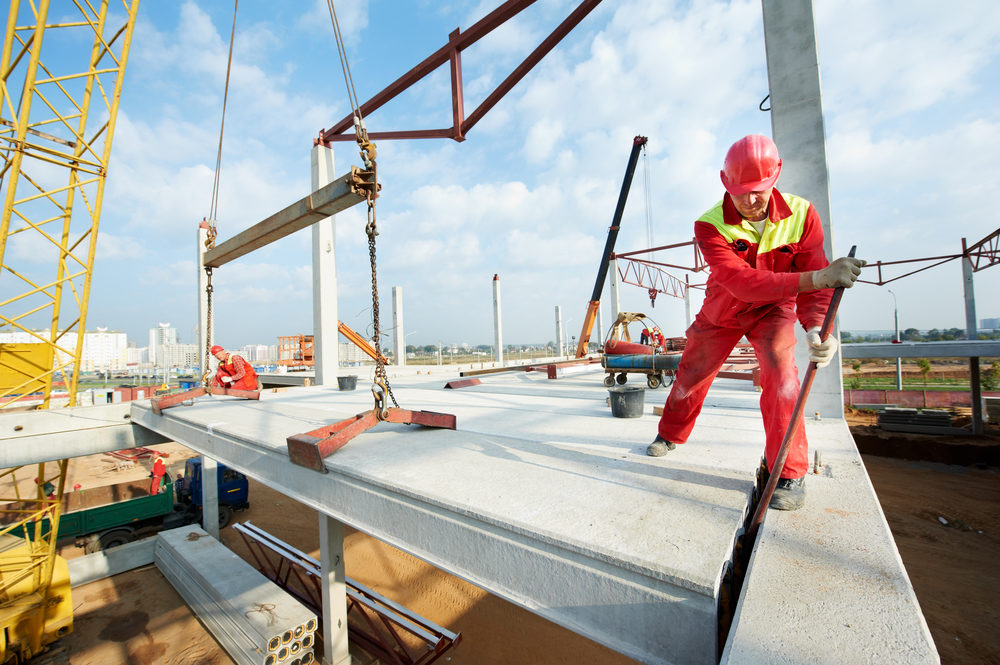 A construction worker wearing safety gear installing a concrete slab