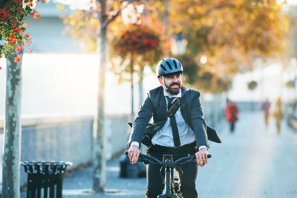 Man wearing suit and helmet riding a bike