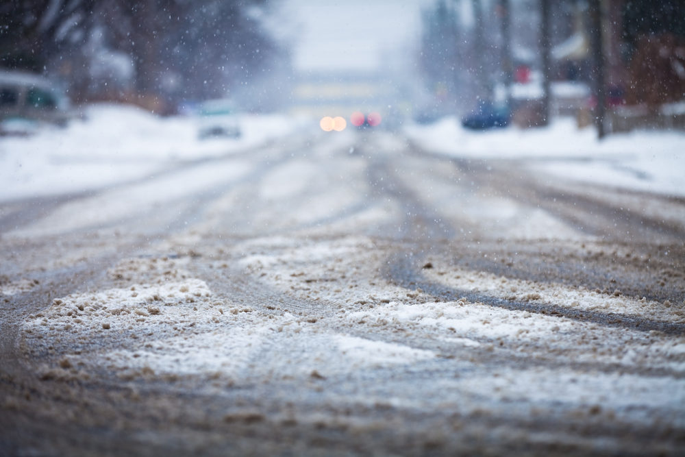 A snow covered city road with tire tracks