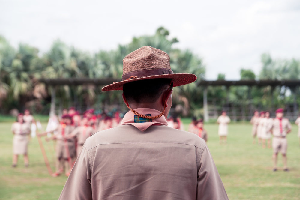 A scout leader looks out over a field of uniformed children