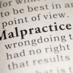 Close-up of the word "Malpractice" in a dictionary