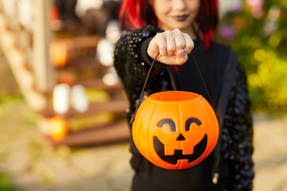 A girl holding out a pumpkin basket for Trick-or-Treating