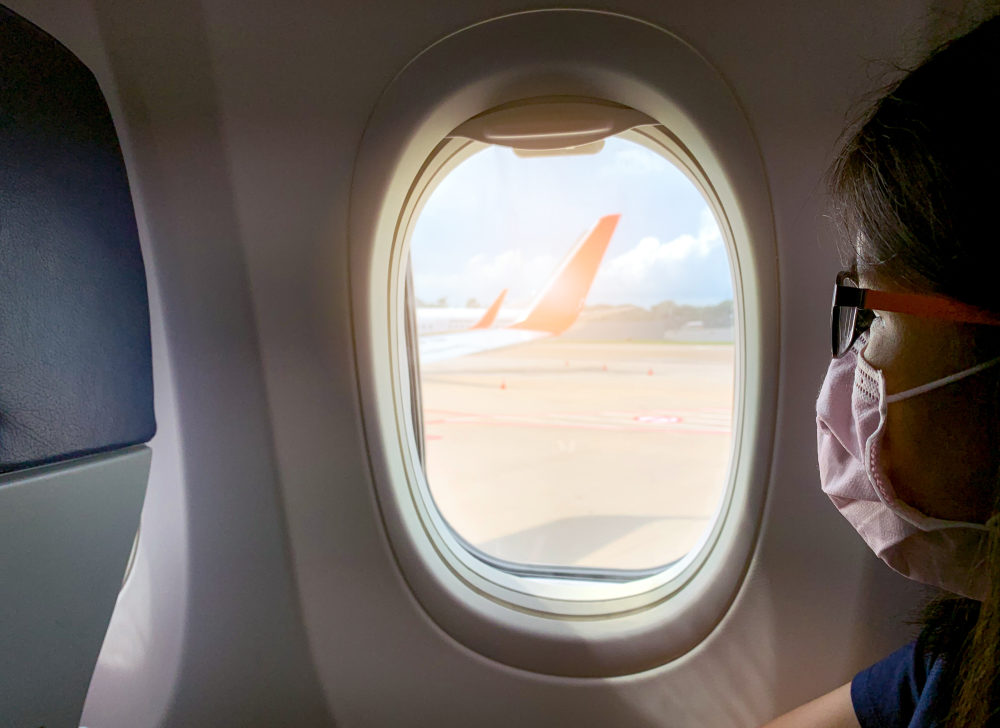 The Latest on the Coronavirus, and What You Need to Know An asian female wearing a respirator mask peers out an airplane window
