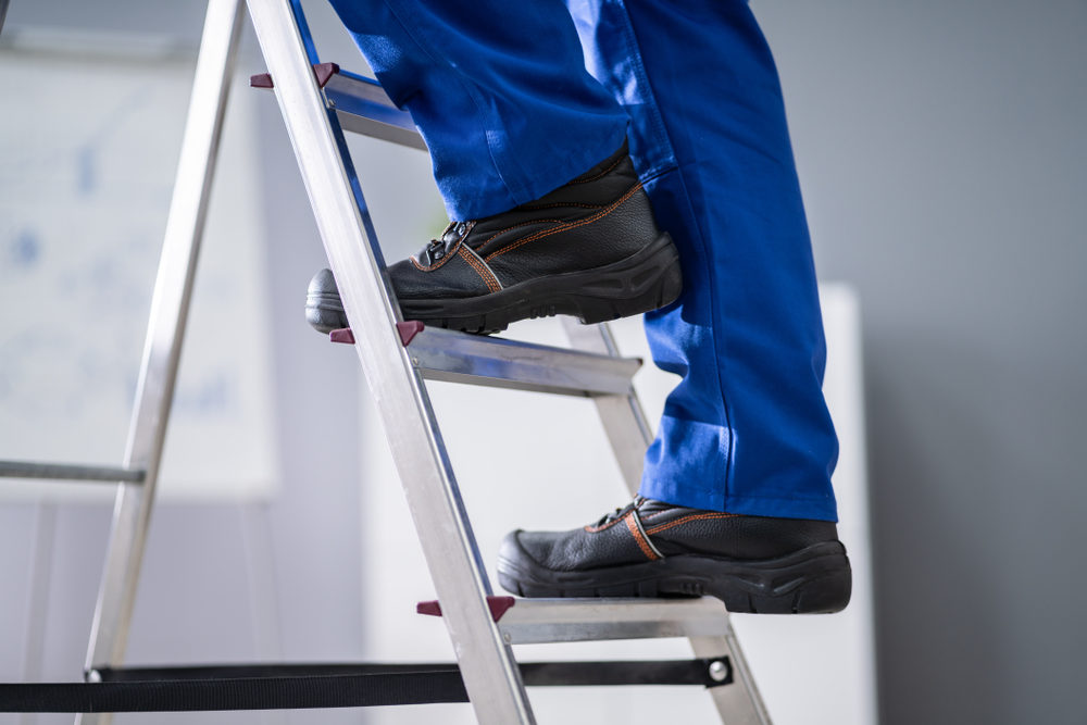 Close-up of shod feet climbing a stepladder