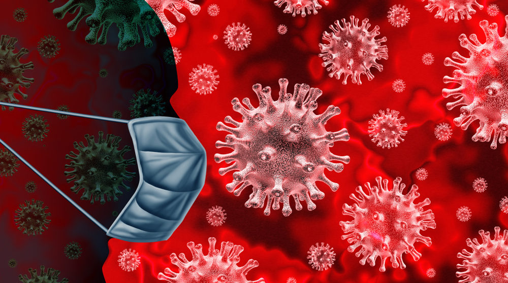 3d rendering of a red coronavirus cell, with a silhouetted masked face on the side