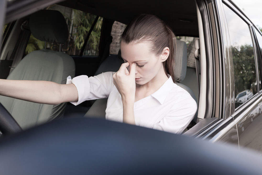 A young woman closes her eyes as she drives a large SUV