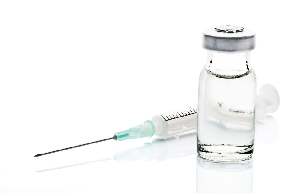 An empty syringe and a clear vial full of liquid on a white background