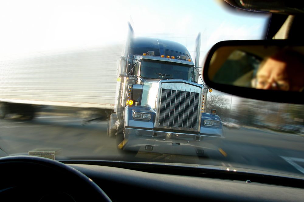 A big rig about to slam into a car head-on, as viewed through the car's windshield