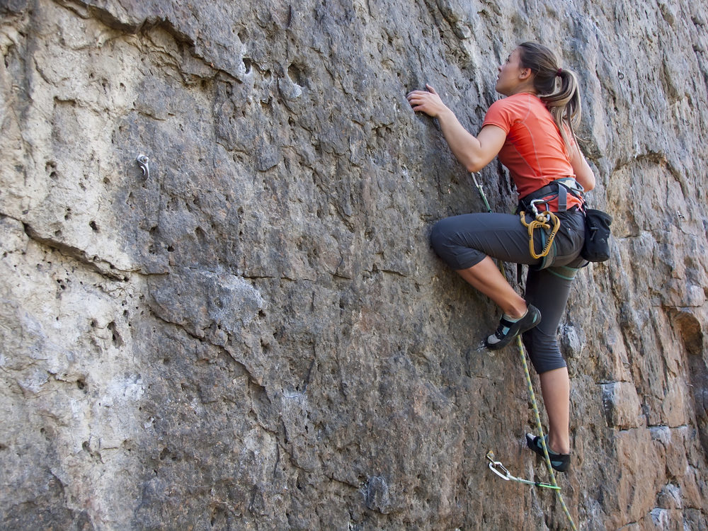 A young woman climbing a very steep cliff