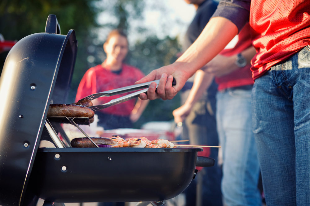 A man grills sausages at a tailgate party