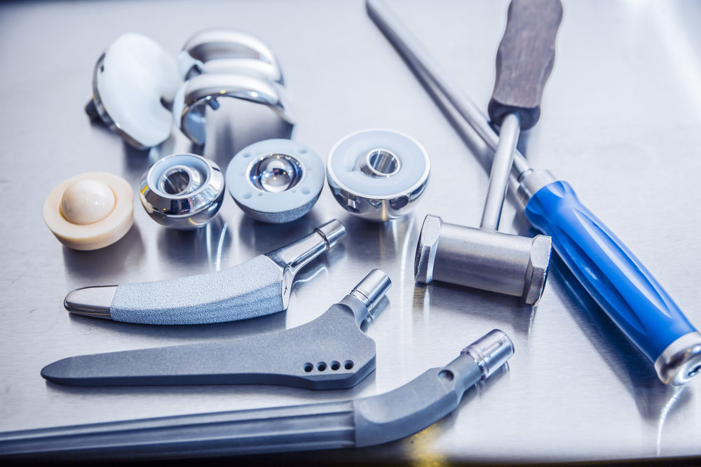 Various parts for hip and leg joint replacement lay on a metal table