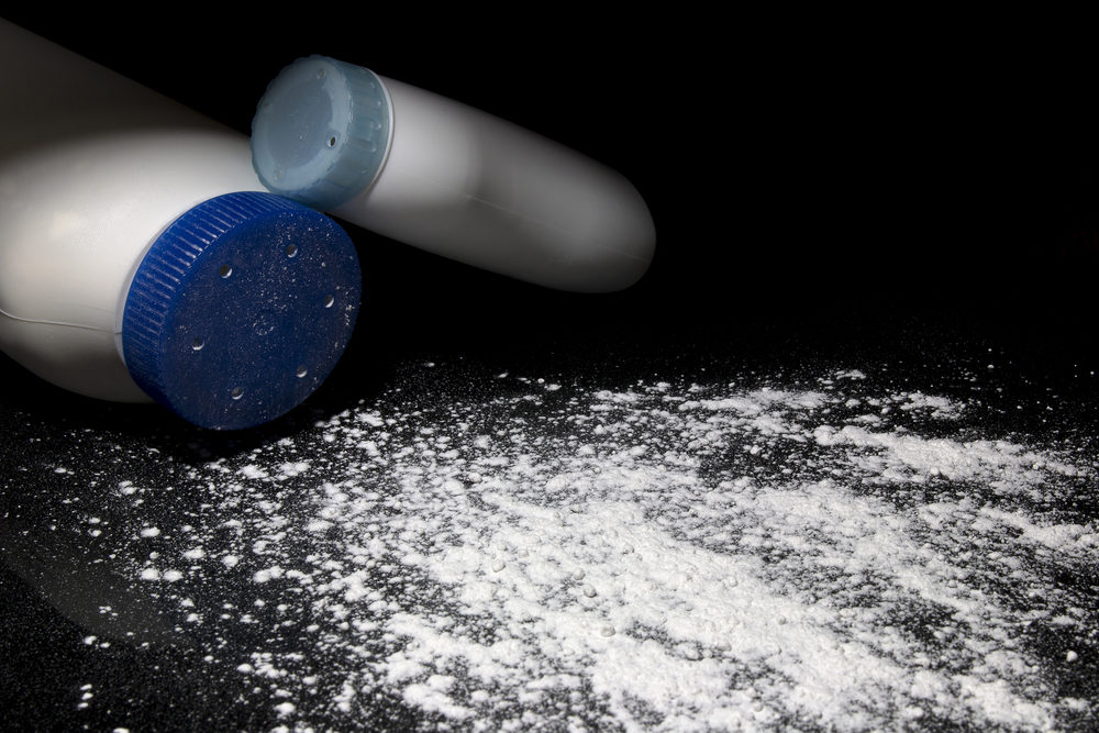 Talcum powder spills from a bottle onto a black surface