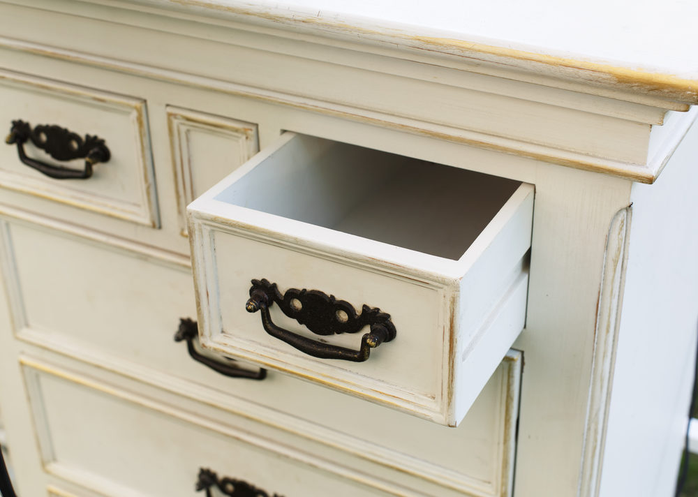 White antique chest of drawers with ornate metal handles