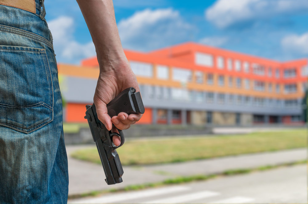A man brandishes a handgun outside a large school