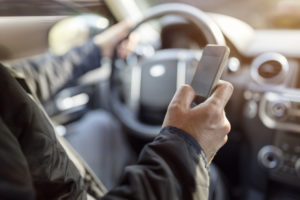 A man sending a text message while driving his car