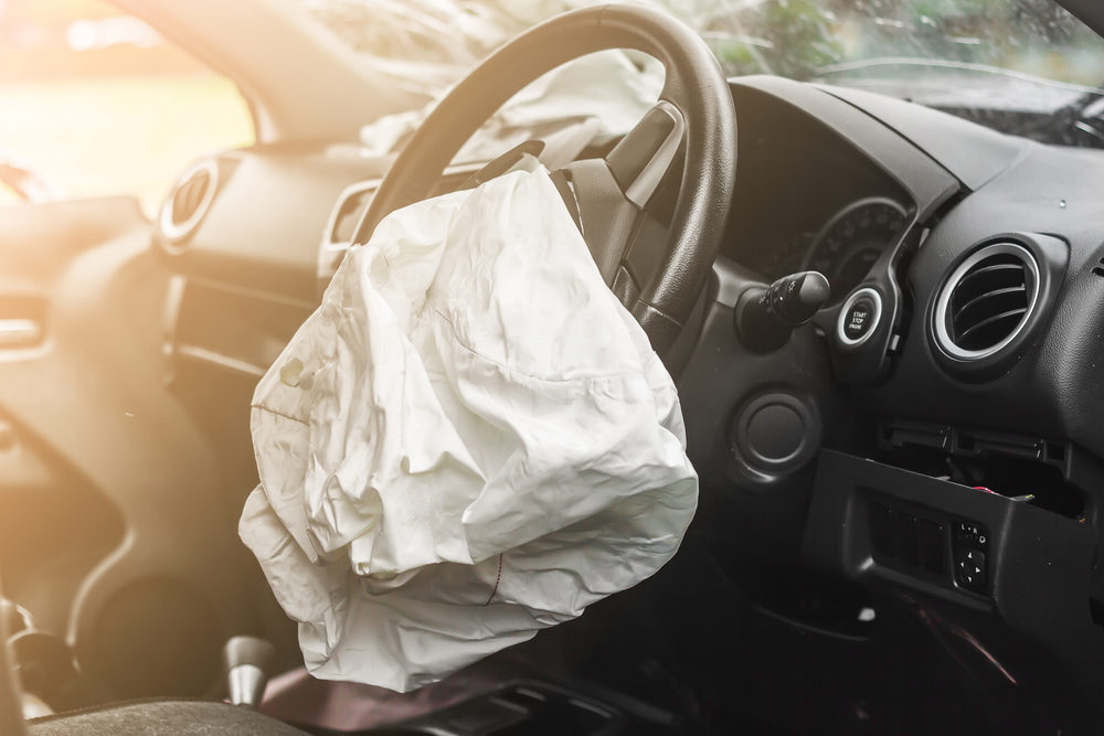 An deployed airbag hangs from a steeing wheel
