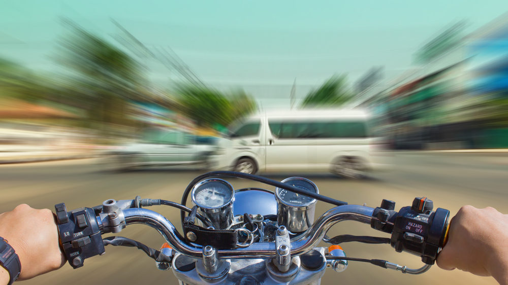 blurred image of a motorcycle heading towards vehicles.