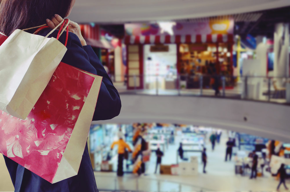 Woman holding shopping bags at a crowded mall