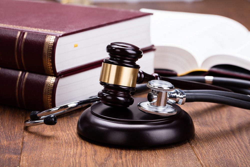 A stethoscope lays next to a gavel and books