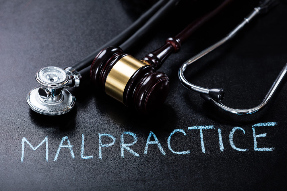 "MALPRACTICE" written in chalk, underneath a stethoscope and gavel