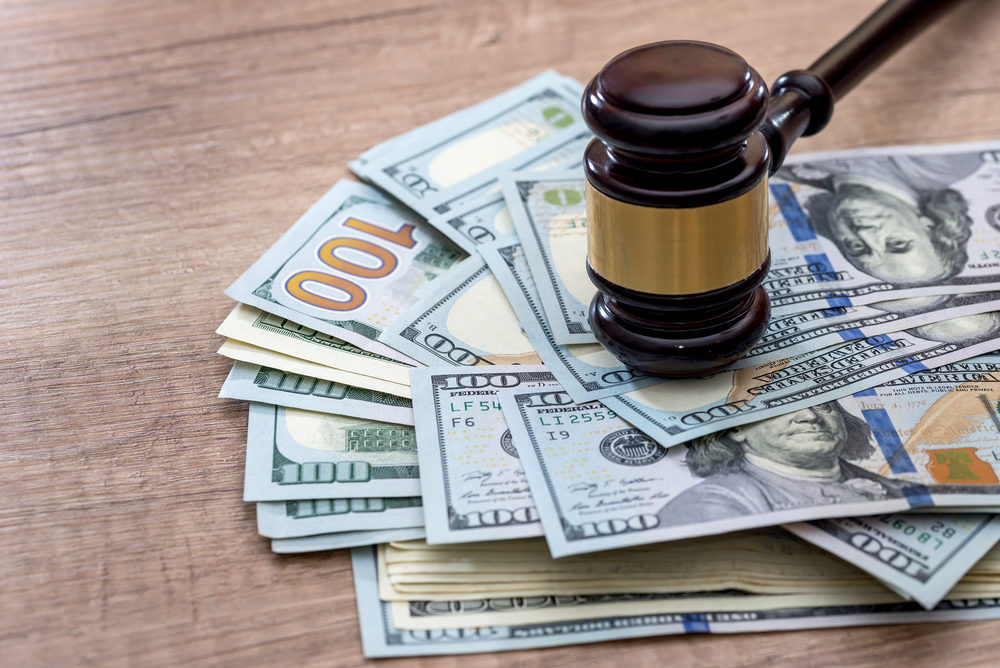 A wooden gavel rests on a pile of American hundred dollar bills
