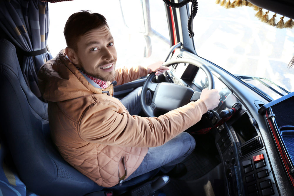 A young man in the cabin of a large truck
