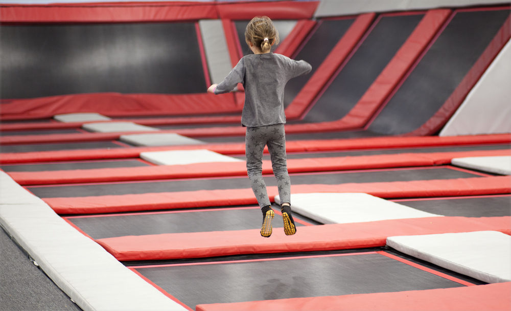 A young girl bounces at a trampoline park