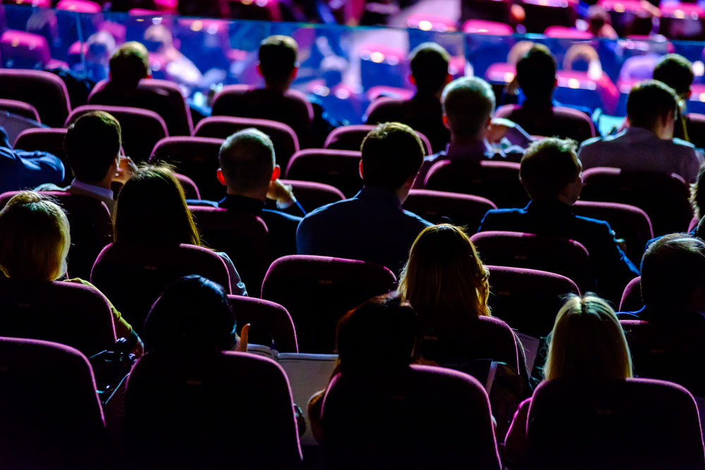 Dimly lit image of people listening in a conference hall