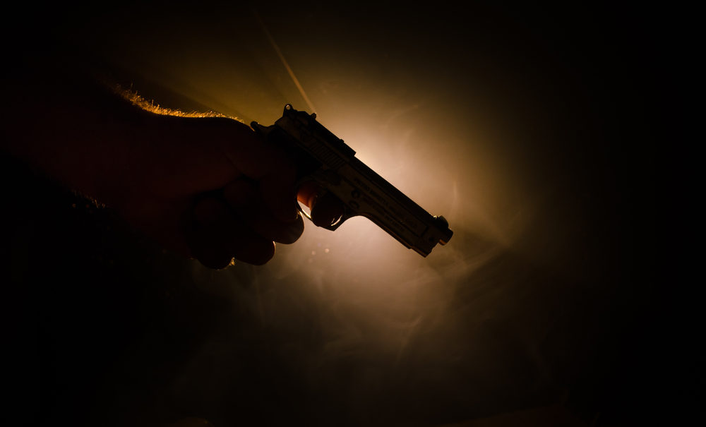 Silhouette of a man\'s hand holding a smoking handgun