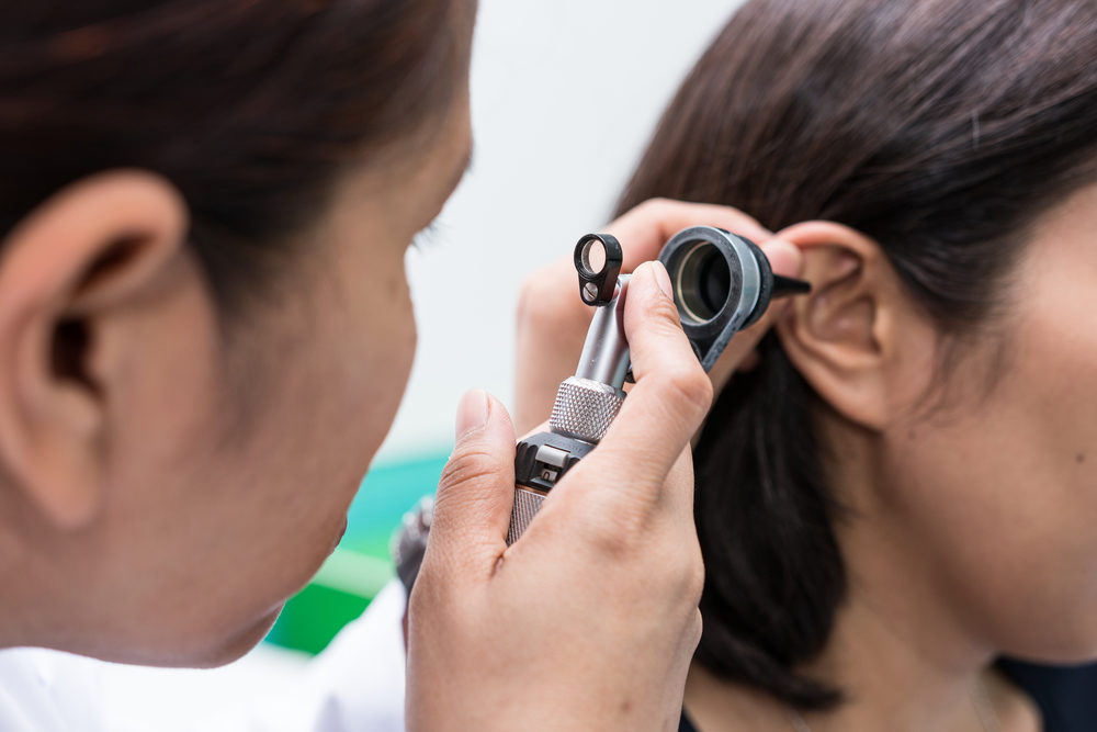 A doctor uses a otoscope to look into a patient's ear