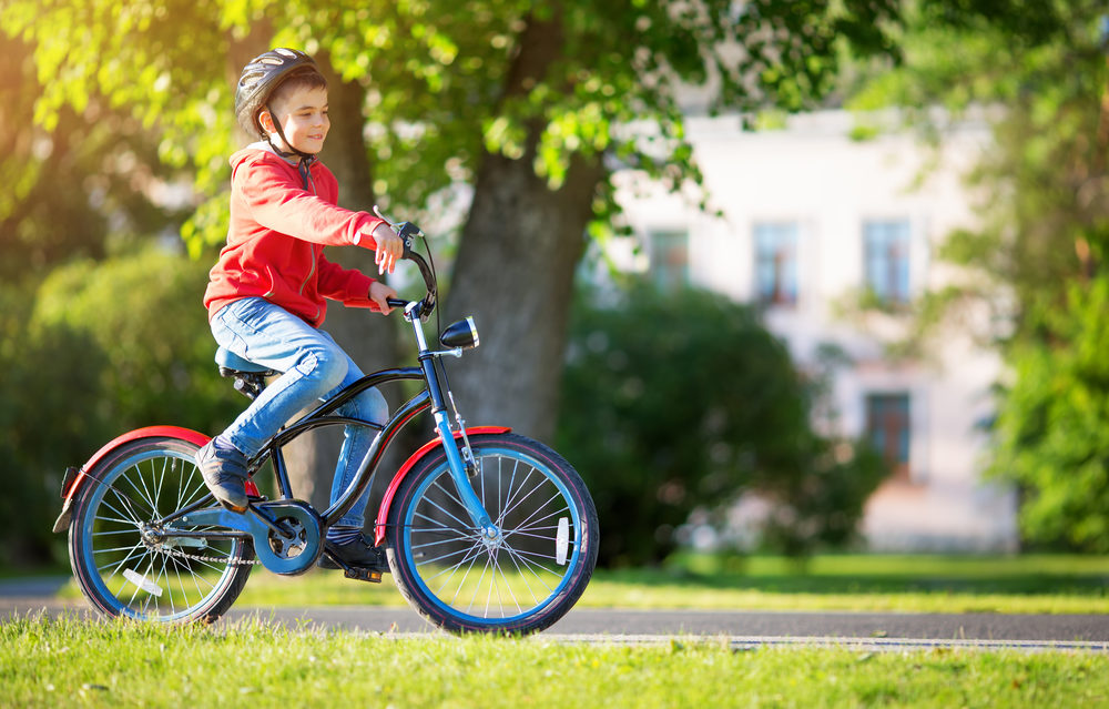 Little boy riding bicycle through park