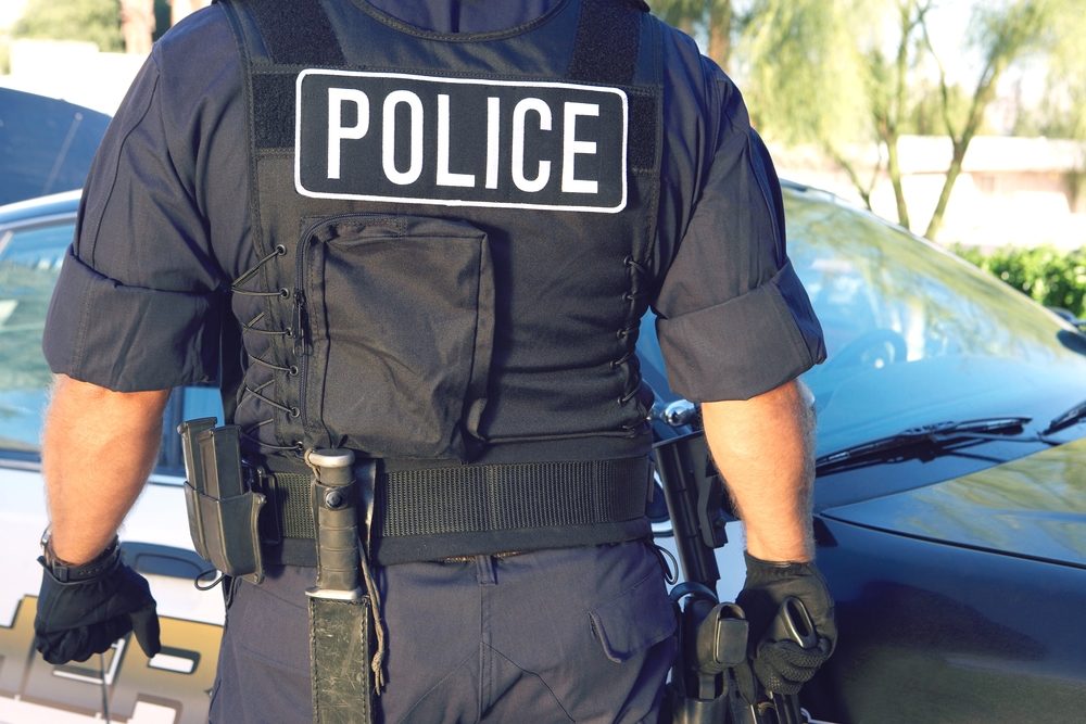 A uniformed police officer heads towards his sheriff vehicle